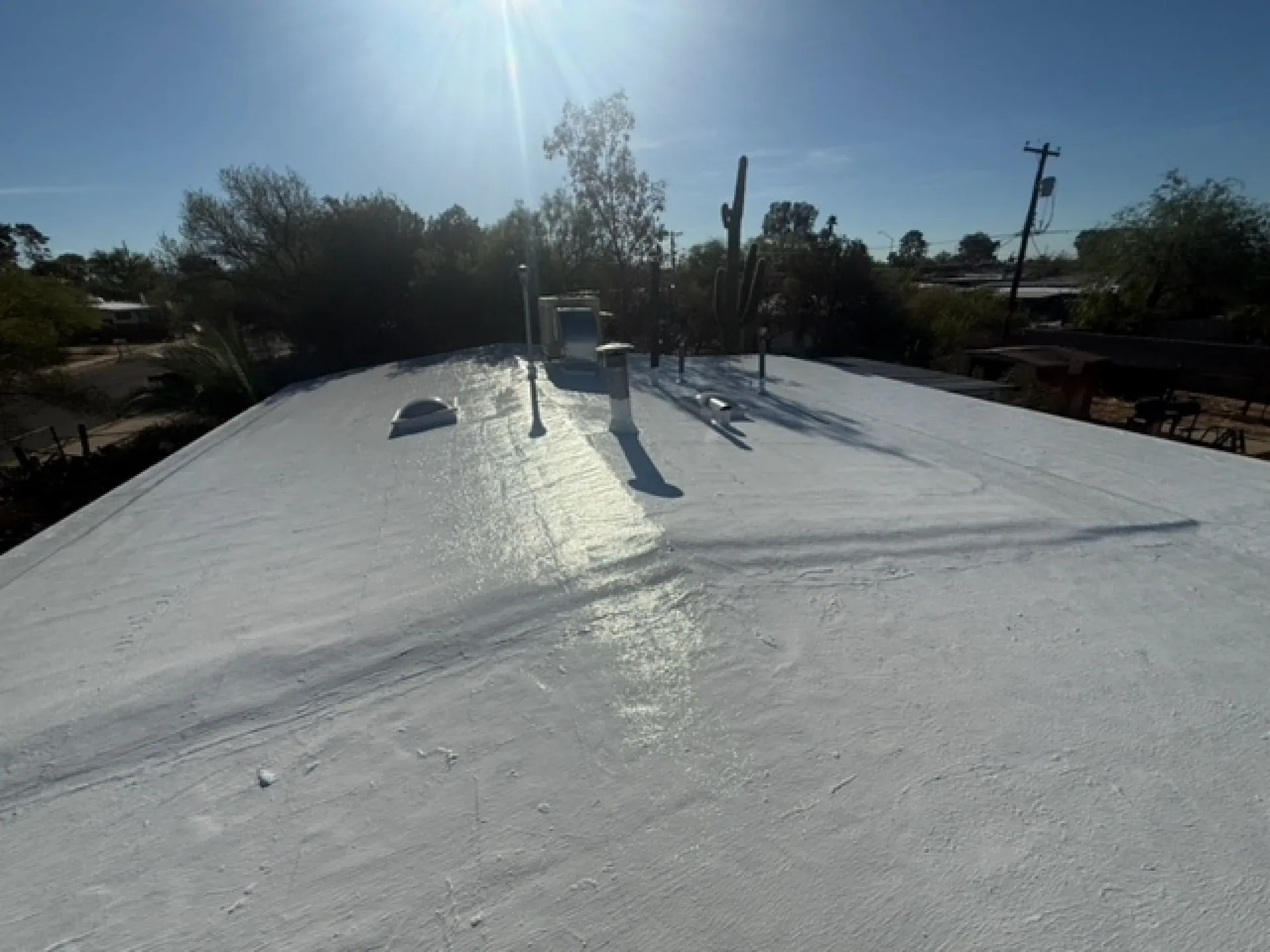Fresh white coating on a Tucson flat roof beside a skylight and vent